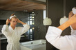 © Wavebreak Media - Young blonde woman looking in the mirror in a bathroom