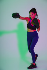 Sticker - Beautiful strong fitness woman boxer isolated with led flash lights make boxing exercises.