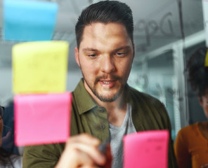 Sticker - Portrait of a businessman brainstorming new startup business and writing on sticky notes stuck on transparent glass in office