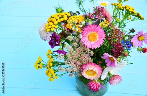 Wunderschöner bunter Blumenstrauß mit Strohblumen auf blauem Holzuntergrund