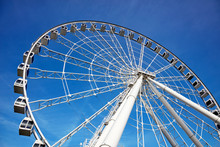 Ferris Wheel On Blue Sky Background In Amusement Park. Majestic View From Below