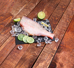 Wall Mural - Sea perch on a black board. sea ​​bass on a black board with ice and lime. Fish on the table. ocean perch  