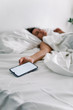 © phpetrunina14 - woman sleeping in bed phone in her hand