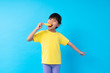 Young Asian girl eating yellow ice cream on blue background in studio