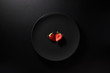 One sliced strawberry served in black plate on moody black background. Top view. Healthy diet concept.