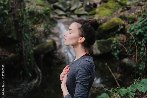Fotografía Young woman practicing breathing yoga pranayama outdoors in moss forest on background of waterfall
