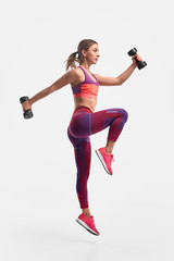 Wall Mural - Athletic woman jumping with dumbbells