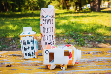 Houses and toy cars made from milk bags on grass. DIY paper milk bag. Creative paper milk bag ideas. Recycle crafts.