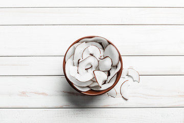 Wall Mural - Coconut chips in a brown bowl on a white wooden background