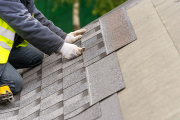 Workman install tile on roof of new house under construction