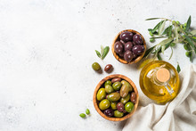 Olives In Wooden Bowls And Olive Oil Bottle On White Background.