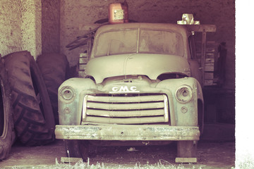 Abandoned truck forgotten in a garage and being overrun by rust and undergrowth