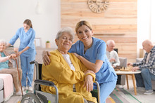 Nurse With Elderly Woman In Wheelchair At Retirement Home. Assisting Senior People