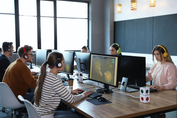 Wall Mural - Group of people playing video games in internet cafe