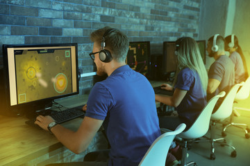 Wall Mural - Group of people playing video games in internet cafe, color tone