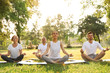 © New Africa - People practicing yoga in park at morning