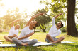 © New Africa - People practicing yoga in park at morning