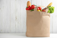 Shopping Paper Bag With Different Groceries On Table Against White Wooden Background. Space For Text