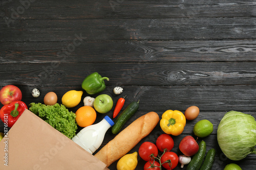 Fotomural Flat lay composition with overturned paper bag and groceries on black wooden background
