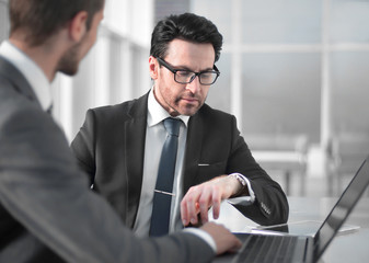 two businessmen discussing information from a laptop.