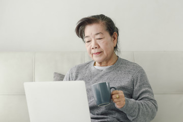 Wall Mural - Asian senior woman using laptop at home, lifestyle concept.