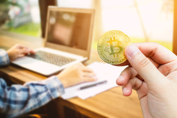 Use hand holding Bitcoin coin blurred images of Abstract blur of businessman casual working with laptop computer and coffee on background,Cryptocurrency exchange concept of electronic payments.