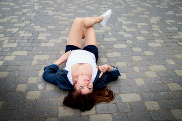 Brunette funny pretty girl on pavement in Central part of ancient city. Walk in downtown. Portrait of girl on street