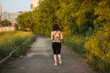 © natalialeb - woman in sports shirt jogging in park at sunset