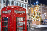 Fototapeta Londyn - Rote Telefonzelle in London vor einem beleuchtetem Weihnachtsbaum zur Adventszeit, Großbritannien