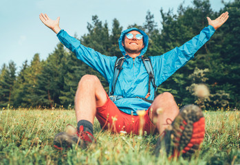 Wall Mural - backpacker man has a rest break enjoying mountain landscape wide opened and raised arms. he wears in