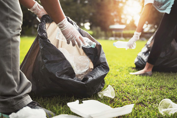 Wall Mural - mother and children keeping garbage plastic bottle into black bag at park in morning light