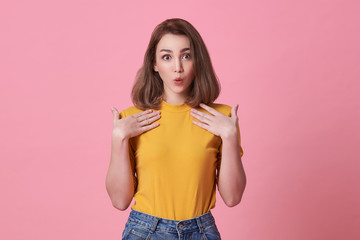 Wall Mural - Excited beautiful woman with mouth open wearing casual yellow t-shirt isolated on pink background.