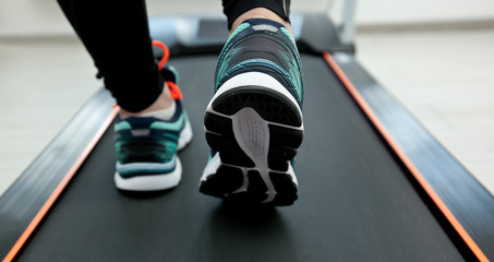 The woman's legs in new sneakers on the treadmill