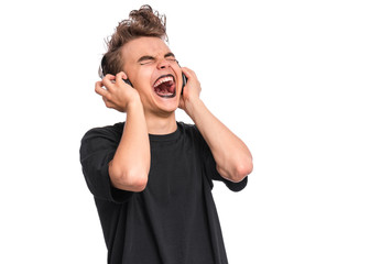 Poster - Rebellious happy teen boy with headphones, isolated on white background. Cheerful child listening to music and singing song. Emotional portrait of teenager in style of punk goth enjoying music.