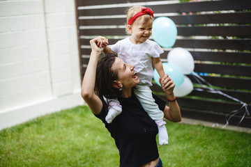 Wall Mural - Mother with little girl, playing happy on the green grass.