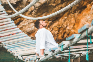 Wall Mural - man sitting at suspension bridge enjoying sea view and nature calmness