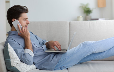 Poster - Serious Guy Having Phone Conversation Lying With Laptop On Couch
