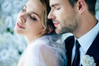 attractive bride and handsome bridegroom in suit with closed eyes