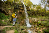 Fototapeta Łazienka - Young hiker stopped beside a mountain waterfall to rest