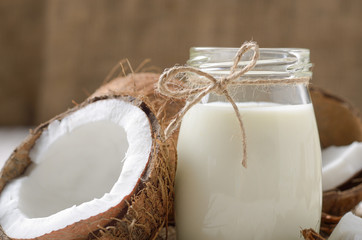 Wall Mural - Milk or yogurt in mason jar on white wooden table with coconut aside