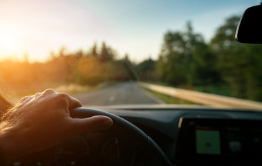 Wall Mural - hands of car driver on steering wheel, road trip, driving on highway road