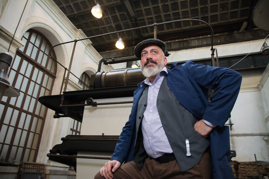 Worker standing in front of a vintage printing press