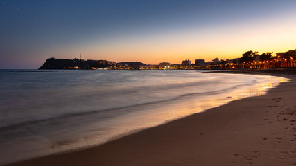 Wall Mural - Panoramic view over the bay of the spanish town Mazarron at the mediterranean sea after sunset. Warm orange light and the lighthouse high on the cliffs.