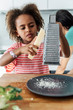 © Westend61 - Girl cooking with mother in kitchen grating cheese