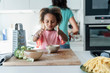 © Westend61 - Girl playing with grated cheese in kitchen