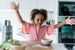 © Westend61 - Girl playing with grated cheese in kitchen