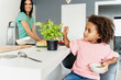 © Westend61 - Girl cooking with mother in kitchen plucking basil leaves