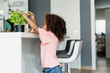 © Westend61 - Girl plucking basil leaves in kitchen