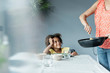 © Westend61 - Mother serving meal for daughter sitting at dining table