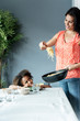 © Westend61 - Mother serving pasta meal for daughter sitting at dining table